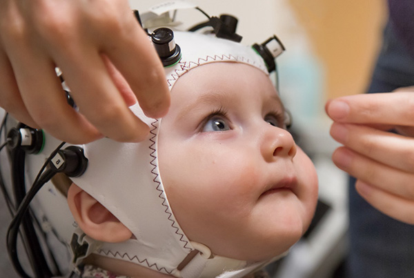 Infant wearing a fNIRS cap allowing to measure changes in the brain hemodynamic response.